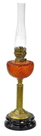 A Victorian brass column oil lamp, with amber tinted glass reservoir and a ceramic base, 71cm high including chimney. (AF)