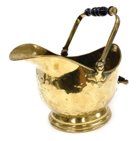 A late 19th/early 20thC brass helmet shaped coal scuttle, with ebonised handles and a domed foot, 43cm high.