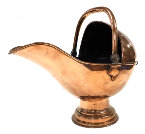 A late 19thC copper helmet shaped coal scuttle, on an associated domed foot with swing handle, 45cm high.