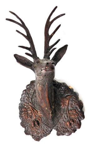 A Black Forest style carved deer shaped wall mask, the mount decorated with oak leaves, acorns, etc., some detail possibly composition, 85cm high.