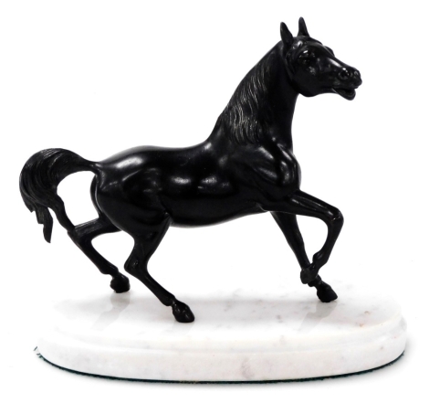 A late Victorian small spelter figure of a horse, in animated pose, raised on a white marble plinth, 14cm high.