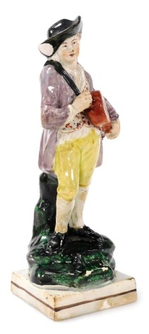 A 19thC Staffordshire pearl glazed figure of a youth with a hurdy gurdy, on a naturalistic base with square foot, 23cm high. (AF)