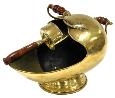 A reproduction beaten brass coal helmet scuttle, having turned treen handles, and a matching shovel.