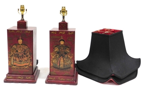 A pair of Chinese simulated red lacquer square section table lamps, decorated with emperor figures, with black square shades, the bases measuring 41cm high.