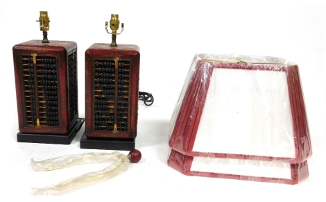 A pair of Chinese simulated red lacquer abacus square section table lamps, the bases measuring 32cm high, with red and white shades.