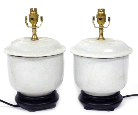 A pair of Chinese crackle glazed porcelain table lamps, in the style of jars and covers, measuring 23cm high, incorporating the wooden stands.