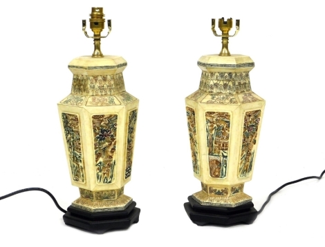 A pair of Chinese simulated ivory hexagonal table lamps, of baluster form, decorated with panels of landscape and flowering shrub decoration, the bases measuring 35cm high.