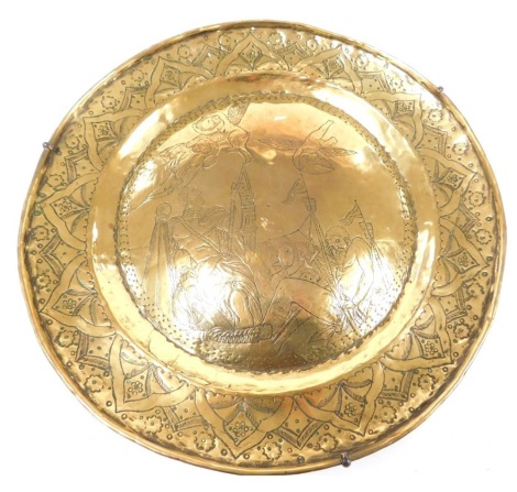 A 17thC brass dish, a central convex roundel engraved with a warrior, Neptune, animals and cherubs, within a foliate and floral border, 34cm wide.