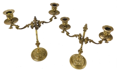 A pair of 19thC brass candelabra, with vertically adjustable arms, raised on an embossed foliate circular base, 30cm high, 25cm wide.