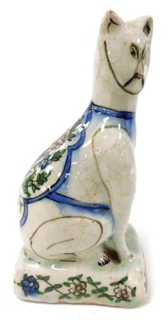 A late 19thC Dutch polychrome Delft ware figure of a cat, modelled in seated pose, its back painted with flowers, raised on a floral painted rectangular base, 19cm high.