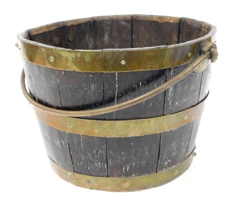 An oak and brass bound fire bucket, with a swing handle, 22.5cm high, 30cm wide.