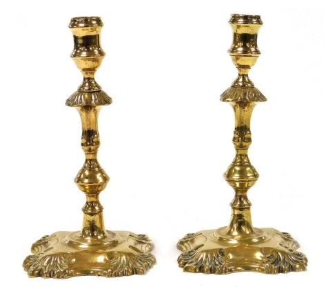 A pair of Georgian brass candlesticks, of fluted and baluster form, raised on a foliate capped square bases, 19.5cm high.