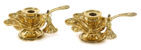 A pair of 19thC brass chambersticks, with shell capped handles, and fluted leaf shaped dishes, each raised on a circular base, with snuffers, 19cm wide.