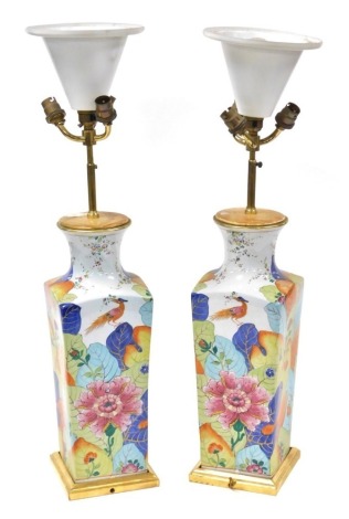 A pair of 20thC Continental porcelain table lamps, of tapering square form, chinoiserie decorated with exotic flowers, leaves and birds, with a quadruple bulb light fitting, raised on a gilt square base, 71.5cm high.