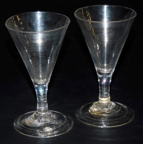 A pair of George III wine glasses, the funnel shaped bowl raised on a straight stem, over a conical folded foot, 10cm high.