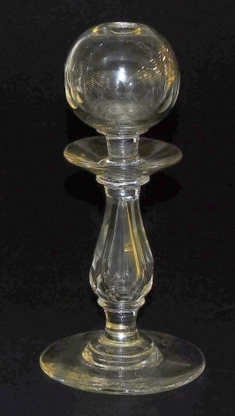 A Georgian glass lace maker's lamp, with a globe form aperture, raised on a baluster turned and faceted stem over a conical foot, 22cm high.