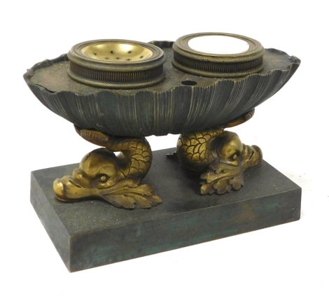 A late 19thC French brass and verdigris desk stand, of oval shell form, raised on double dolphin supports, over a rectangular base, 16cm wide.