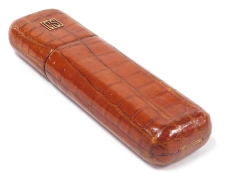 An early 20thC Dunhill crocodile skin cigar case, of oblong form, the lid opening to reveal two compartments, 20cm wide.