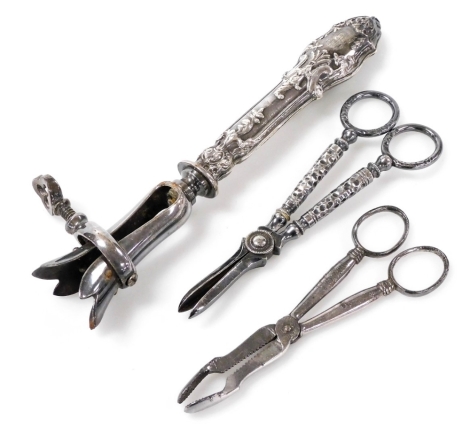 A French silver handled ham brace, the handle embossed with foliate decoration, 21cm long, together with a pair of scissor servers and a pair of grape scissors, (3).