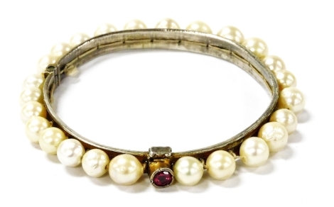 A cultured pearl set bangle, in white metal, with a paste set clip, 7cm wide.