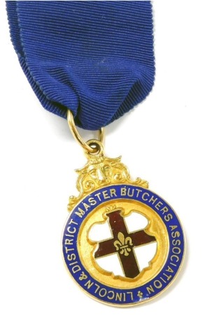 A 9ct gold and enamel jewel, for the Lincoln and District Master Butchers Association, with central reserve shield, reverse engraved to W. Rawlinson, President 1936-1937, on a blue sash, Birmingham 1937, 25.4g all in.