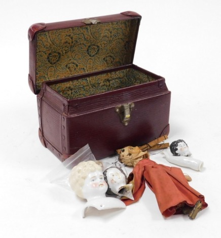 A group of early 20thC porcelain doll parts, to include heads, arms, etc., (AF), contained in a dark red leather case, and a marionette doll.