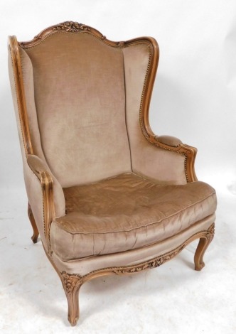 A Victorian style stained framed wingback armchair, with four carved crest rail upholstered in overstuffed brown draylon, raised on foliate carved cabriole legs, 71cm wide. The upholstery in this lot does not comply with the 1988 (Fire & Fire Furnishing) 