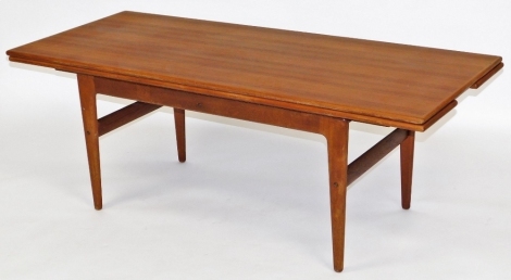 A mid century teak coffee table, the rectangular top with a mechanism to underside extending the table, with a further leaf to each side, raised on tapering legs united by stretchers, 52cm high, the top 60cm x 140cm, extending by a further 24cm to each si