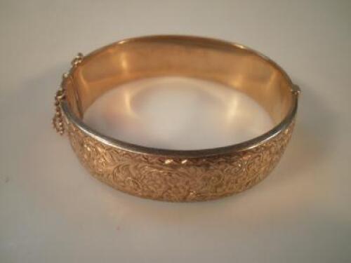 A 9ct gold hinged bangle engraved with scroll motif