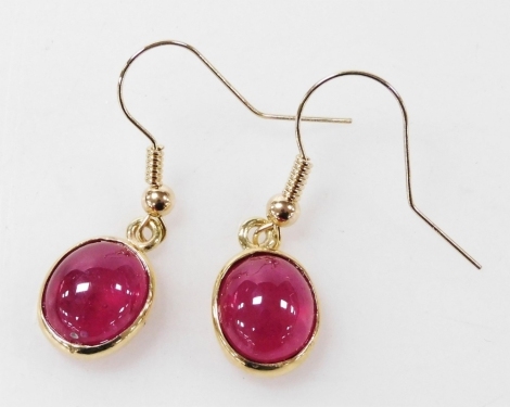 A pair of 9ct gold and ruby cabochon earrings, in an oval setting, with fish hook attachments, 3.7g.