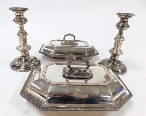 A pair of Victorian silver plated entree dishes and covers, of octagonal form, with gadrooned detailing, together with a pair of Victorian silver plated telescopic candlesticks, embossed with foliate scrolls, 22cm high. (4)