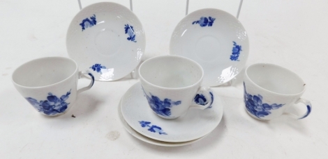 Three Royal Copenhagen porcelain coffee cups and saucers, painted in blue and white with flowers, printed marks.