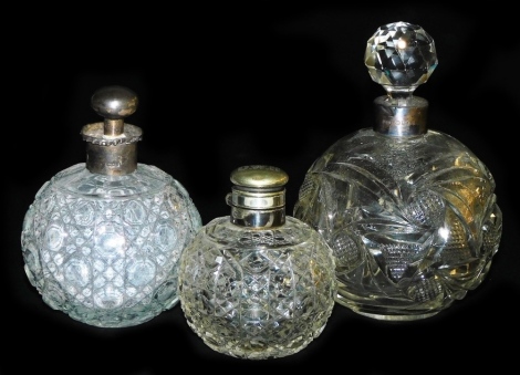 An Edward VII cut glass scent bottle and stopper, with silver mount, Birmingham 1901, cut glass scent bottle with silver mount and stopper, London 1908, and a further cut glass scent bottle with a plated mount and hinged lid. (3)