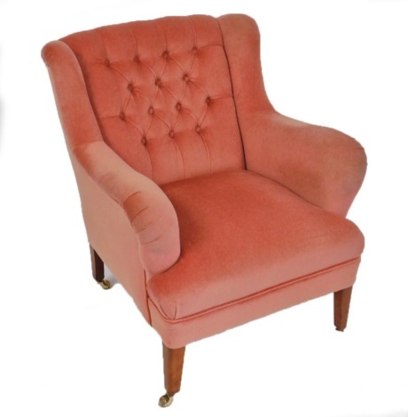 A mahogany framed armchair, upholstered in button back pink draylon, raised on turned legs, on brass castors, 71cm wide.