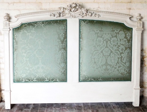 A Continental cream painted headboard, the crest decorated with torches, floral wreath, etc., with two padded panels, on plain supports, 153cm high, 200cm wide.