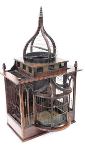 A 19thC Oriental hardwood and copper wire bird cage, of architectural form, with a domed top, tapering finials (1 lacking), the base with stylised bay window, 41cm wide.