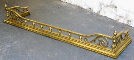 A Victorian brass fender, with spindle turned supports and scroll decoration, on a plinth base, 131cm wide.