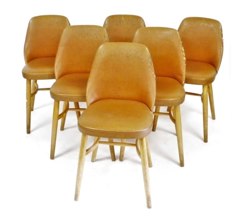 A set of six 1950s brown leatherette dining chairs, with a padded back and seat, on turned tapering legs with concave stretchers. The upholstery in this lot does not comply with the 1988 (Fire & Fire Furnishing) Regulations, unless sold to a known exporte