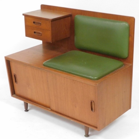 A Jentique mid century teak telephone table, with a green leatherette seat, and two small drawers to the upper section, above a pair of cupboard doors, raised on turned legs, brass capped, 75cm high, 84.5cm wide, 42.5cm deep.