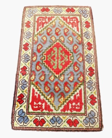 A Turkish blue and red ground rug, decorated with central medallions, within in a field of botehs, and geometric motifs, within a fall border, 150cm x 90cm. (AF)