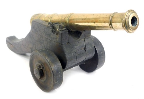 An early 19thC brass table cannon, bears crown and W touch mark, on a stepped wooden base, 17cm high, 38cm wide.