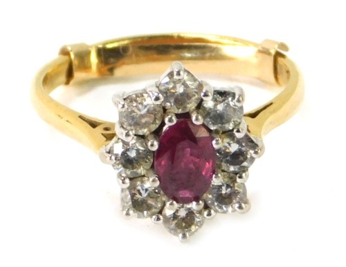 An 18ct gold ruby and diamond cluster ring, the oval ruby in an eight claw setting, surrounded by eight round brilliant cut diamonds, each approx 0.08ct, in white gold, on a yellow metal band, with 9ct gold ring size adjuster, ring size L½, 3.6g all in, b