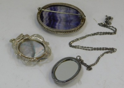 Three Blue John and Blue John style pendants, comprising one with a scroll borders, 3cm x 2.5cm, one in silver frame with a chain marked 925, and another formed as a brooch, with white metal border, unhallmarked but bearing initials H/M 4cm x 3cm. (3) - 2