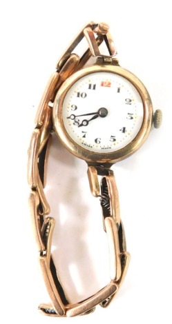 An early 20thC lady's 9ct gold wristwatch, with a circular watch head, with white enamel numeric dial with gold markers, black hands, in a 9ct gold case, on expanding bracelet, 16.1g all in.