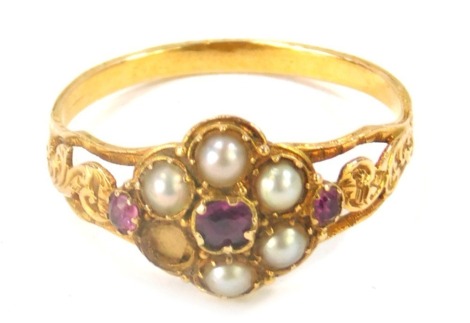 A Victorian memorial ring, the central design set with seed pearls and garnets, with twist design shoulders and open work back, lacking panel, and a cluster pearl, ring size O, yellow metal unmarked, 1.8g all in. (AF)