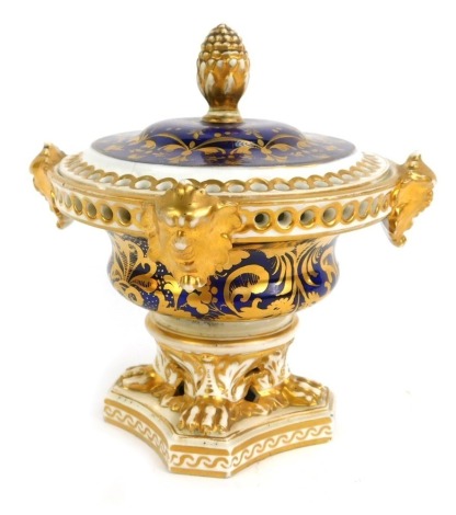 An early 19thC Derby porcelain pot pourri jar and cover, decorated with four handles to the base, a pineapple finial, decorated overall in gilt, on a cobalt blue ground, the base with three paw feet, on a concave platform, painted marks to underside in re