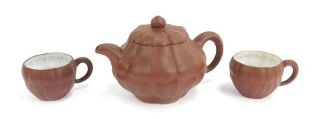 A Chinese red ware lobed teapot and cover, with circular finial and circular impressed mark to underside, 17cm wide, and two similar cups, each with rectangular marks. (3)