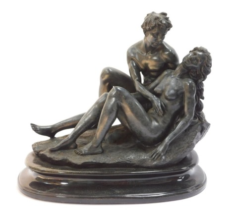 A resin bronze effect figurine of a male and female recumbent lovers, on an oval base, 25cm high, 26cm wide.