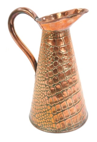 A late 19thC/early 20thC copper jug, with crocodile skin hammered design, 29cm high.