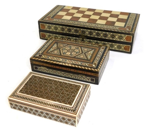 Three Middle Eastern inspired storage boxes, all with bone and mother of pearl inlaid design, including a games compendium box, the largest 7cm high, 30cm wide, 15cm deep.